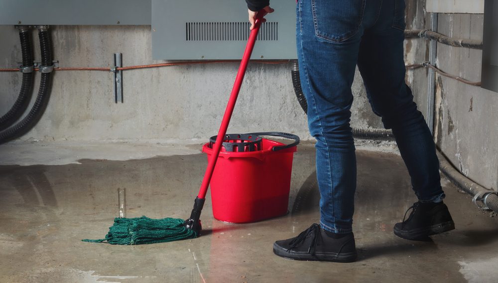 person mopping and cleaning a flooded basement